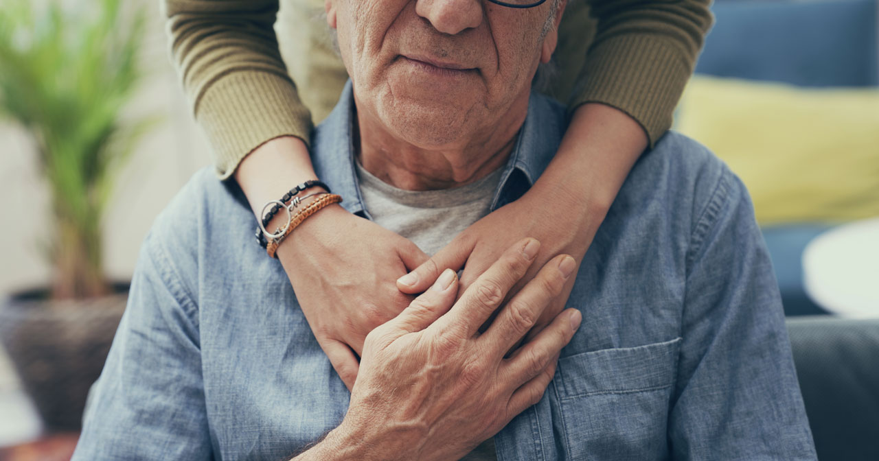 Photo of man with woman's arms holding him affectionately